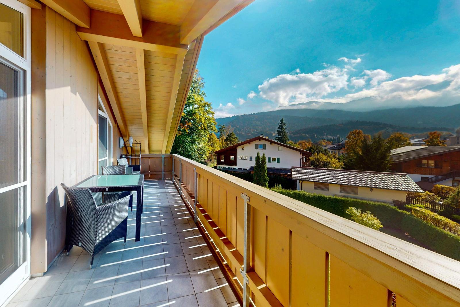 Terrasse mit Tisch und Stühlen bietet Aussicht auf Berge und Wohnhäuser.