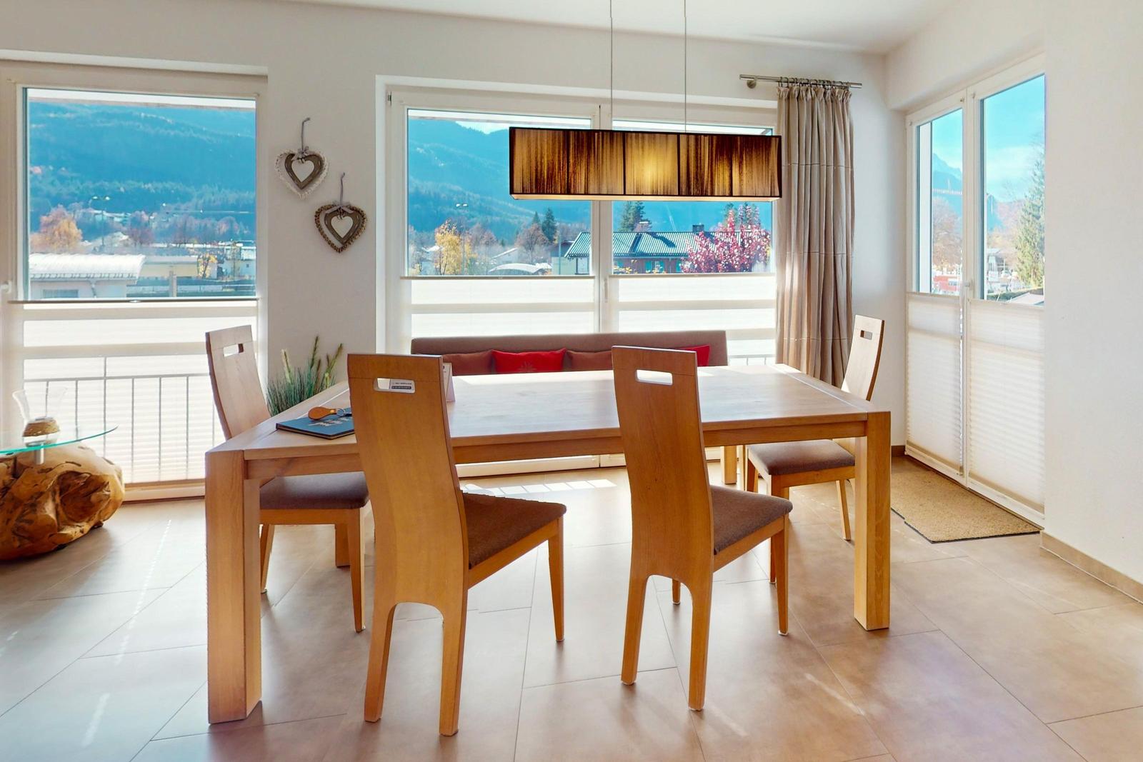 Esszimmer mit Holztisch, Stühlen und Blick auf Berge.
