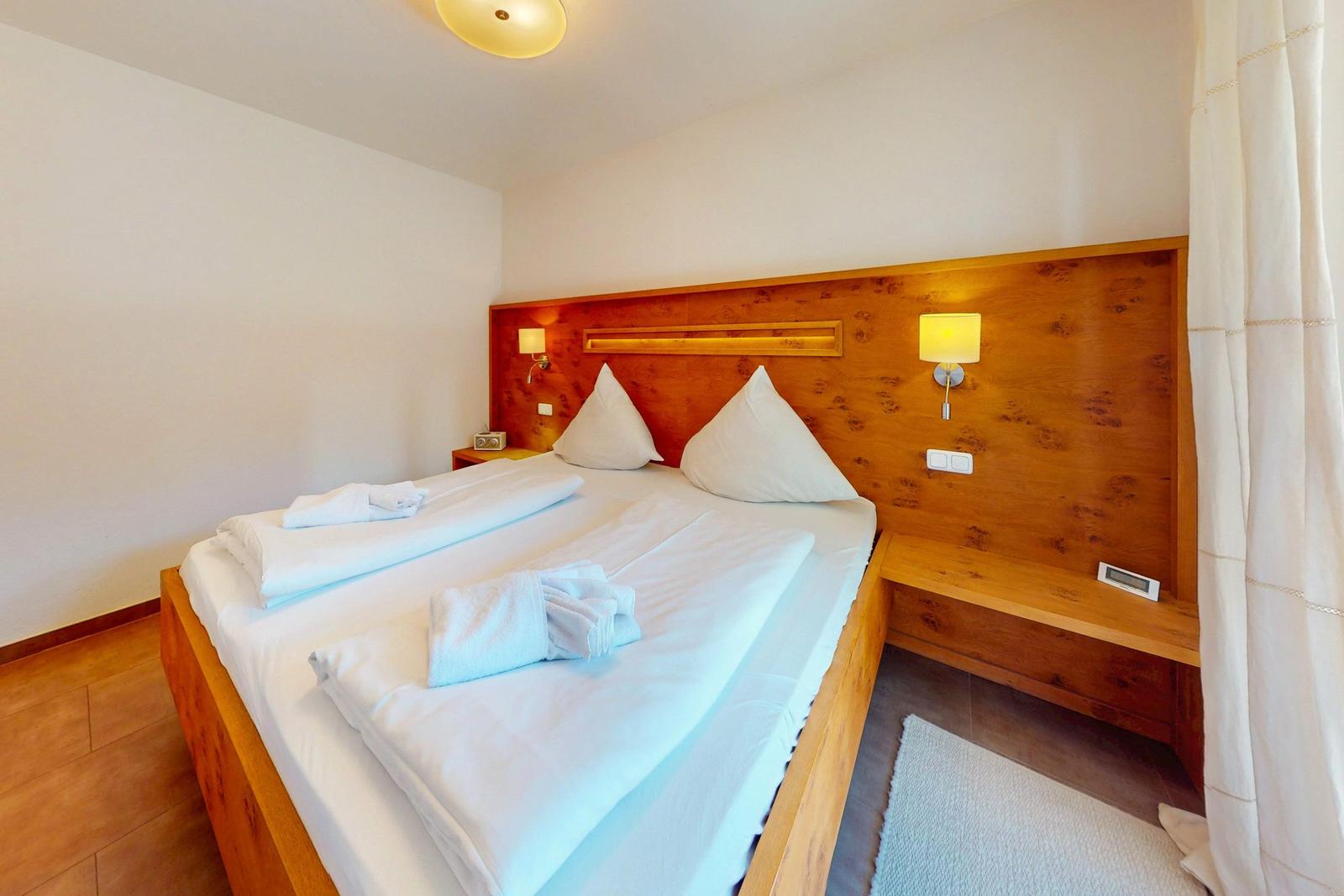 Schlafzimmer mit Holzbett, weißen Bettwäsche und integrierten Nachttischen.