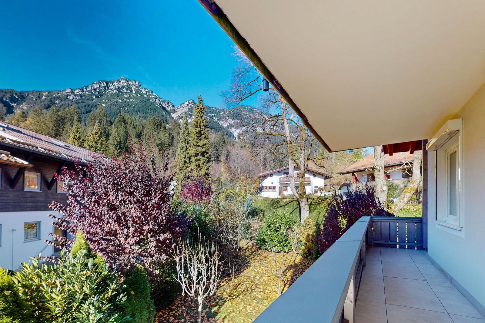 Terrasse mit Blick auf bewaldete Berge und umliegende Häuser.
