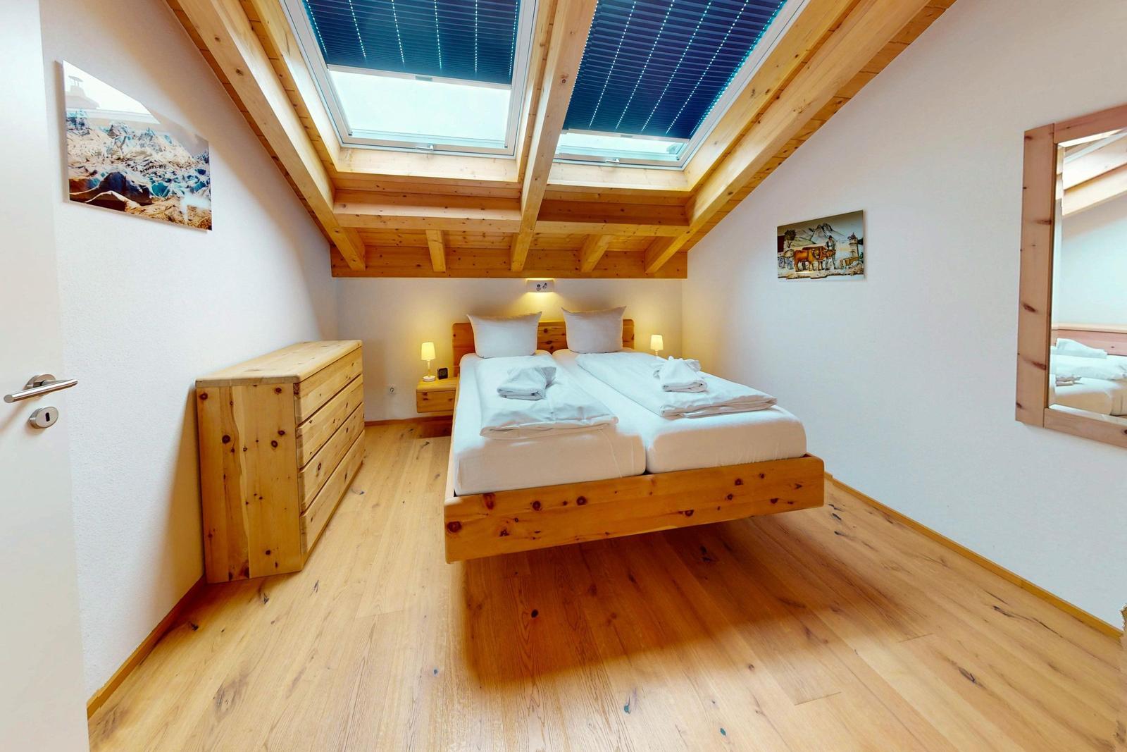Schlafzimmer mit Doppelbett, Holzmöbel und Dachfenster.