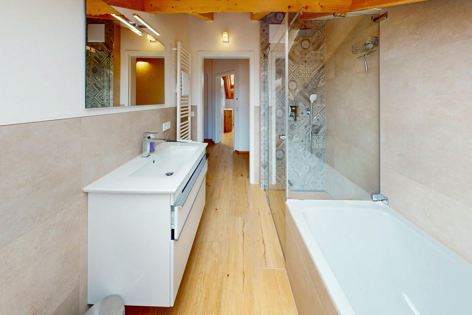 Badezimmer mit Dusche, Badewanne und Waschbecken mit Spiegel.