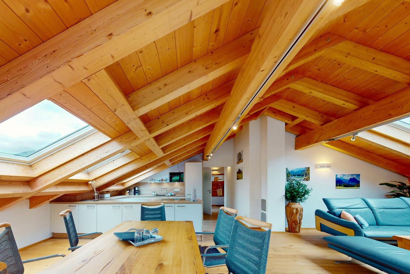 Dachgeschosswohnung mit Holzdecke, Essbereich und Wohnbereich mit Sofa.
