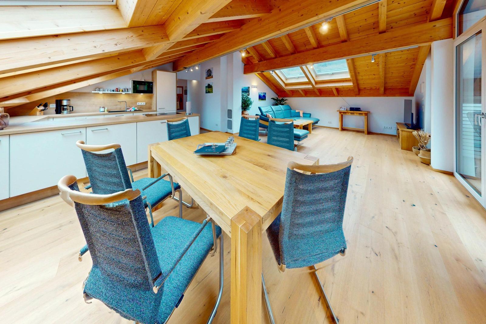 Großer Raum mit Essbereich, Küche und Wohnbereich unter Holzdecke mit Dachschrägen.