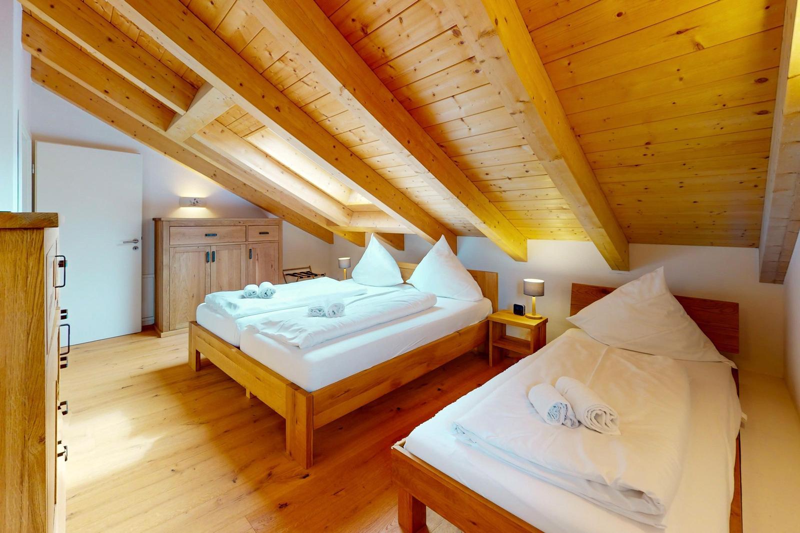 Zimmer mit zwei Betten, Holzboden und Holzdecke mit Balken.
