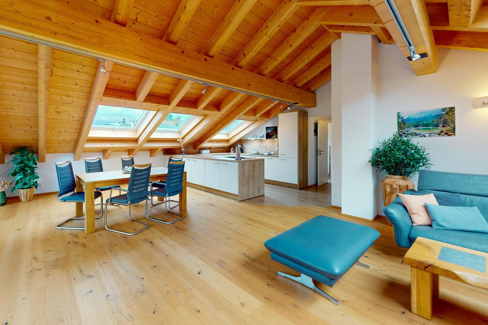 Wohn- und Essbereich mit Holzdecke, Küchenzeile und Sofa.