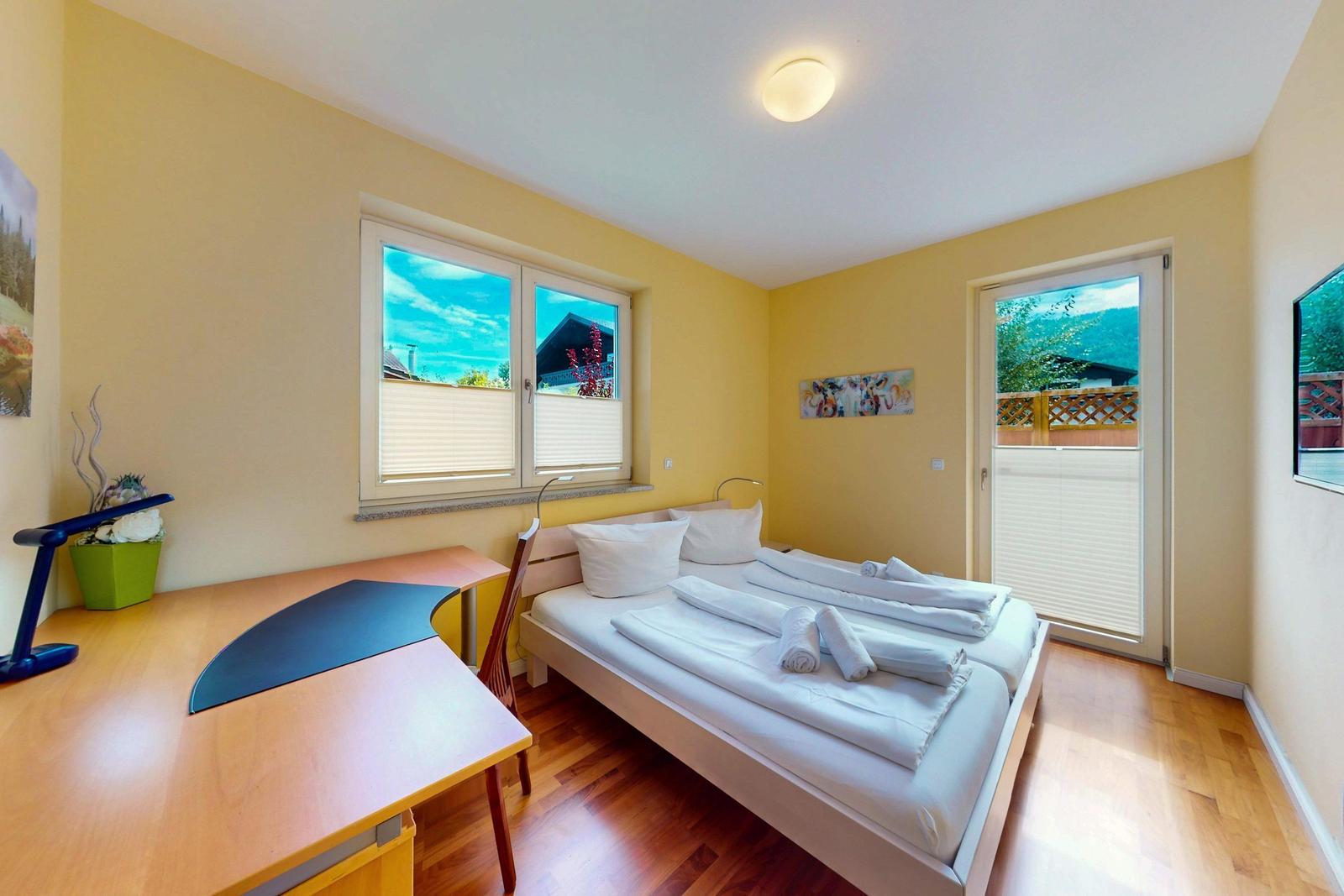 Ein Schlafzimmer mit Doppelbett, Schreibtisch und Blick auf die Berge.