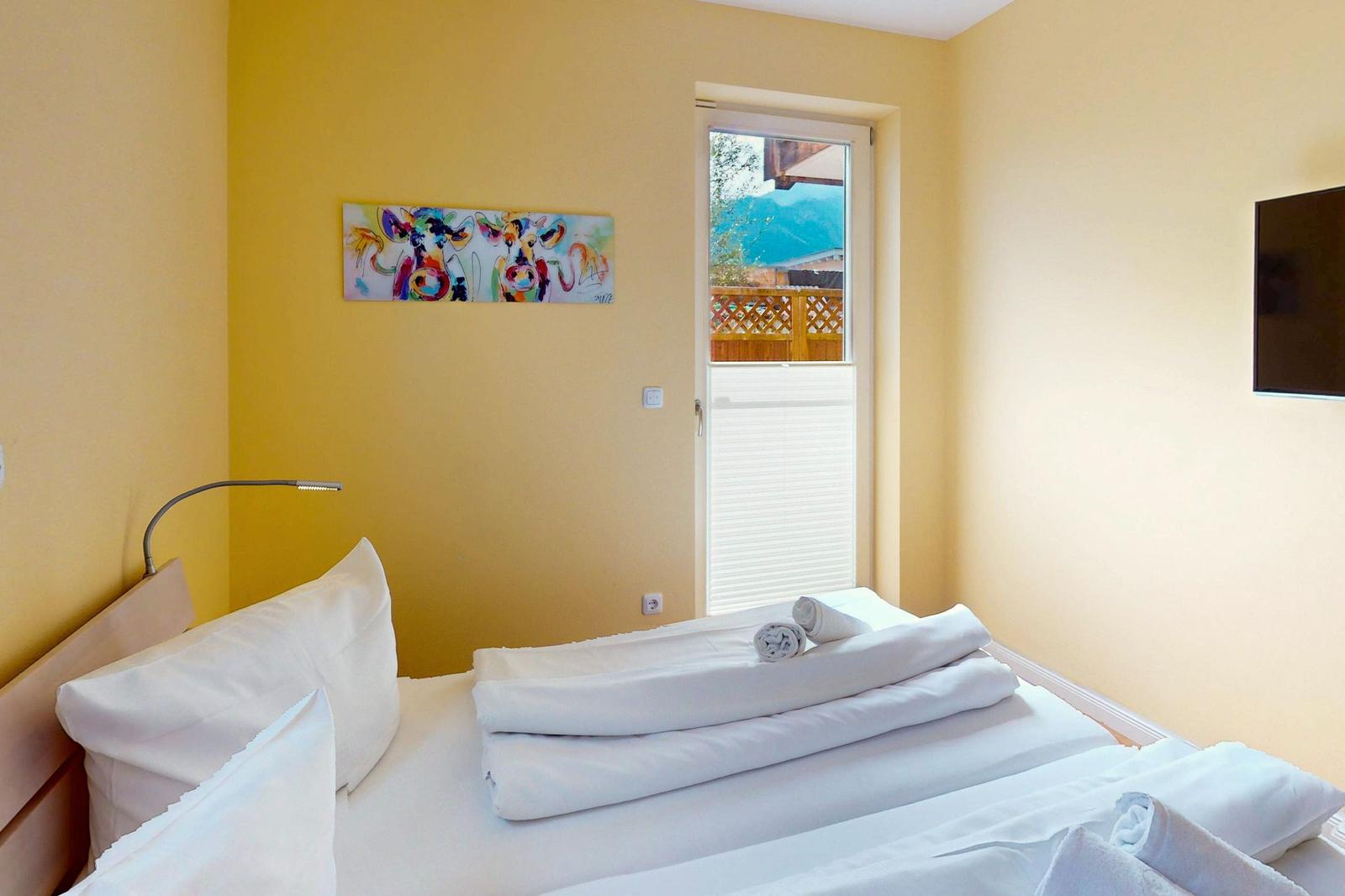 Ein Schlafzimmer mit Bett, Wandbild und Tür zum Balkon.