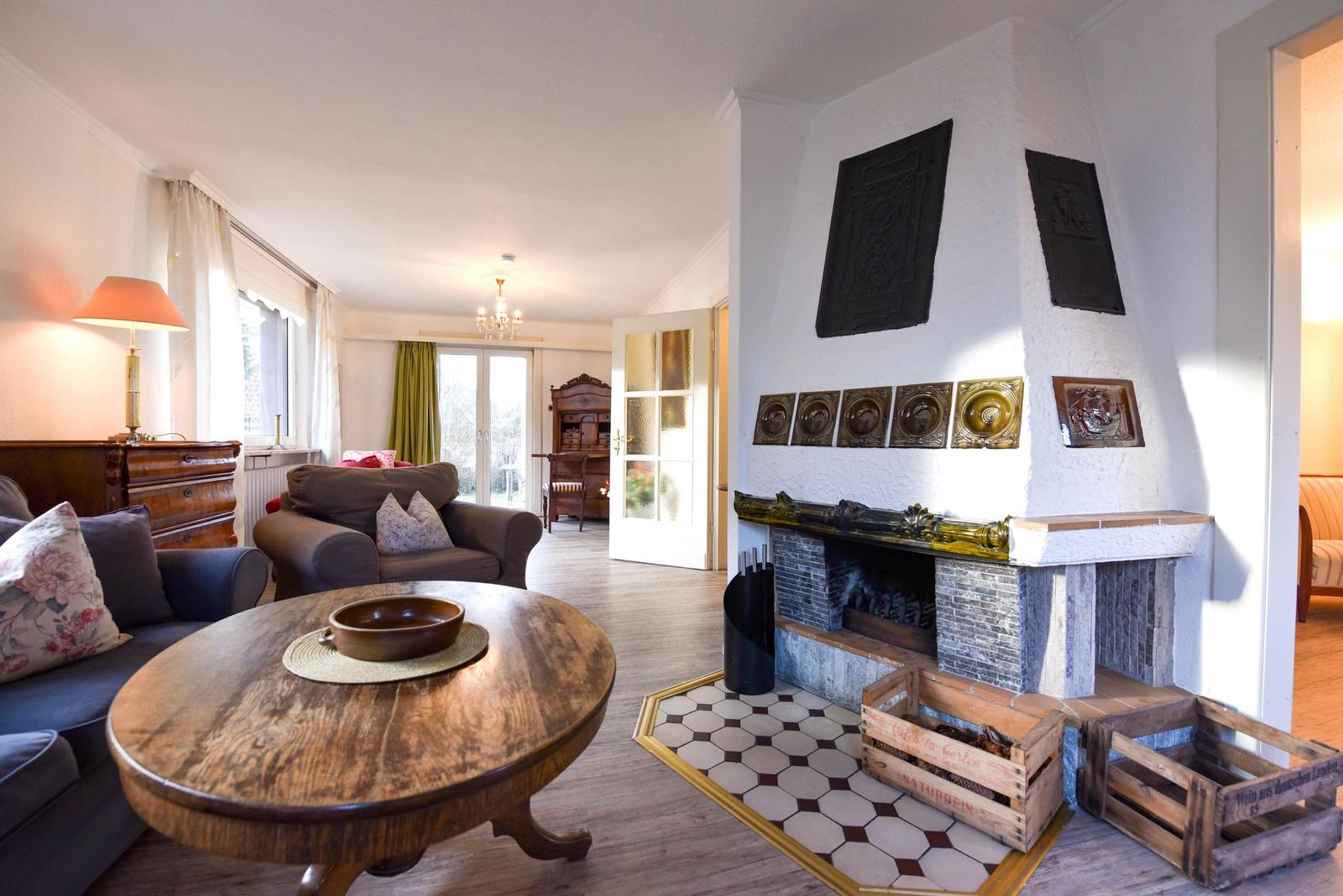 Wohnzimmer mit Kamin, Holztisch und Sofa. Flur mit Türen und Möbeln.