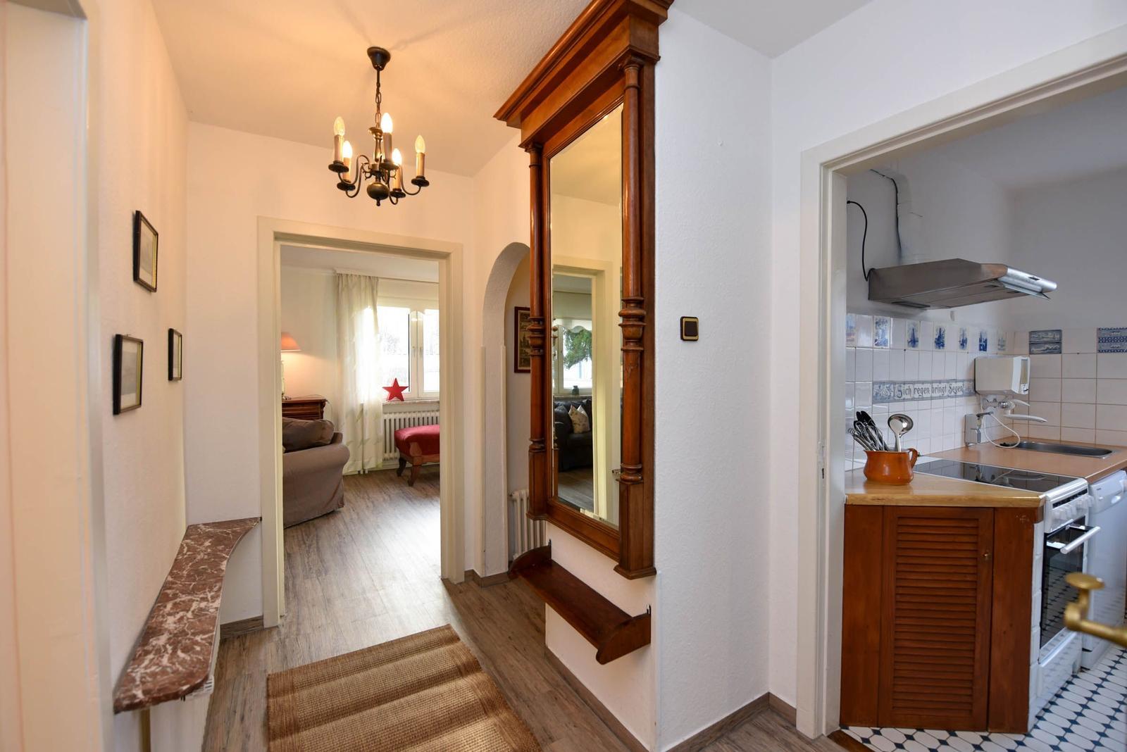 Hausflur mit Spiegel, Küche und Blick in Wohnzimmer.