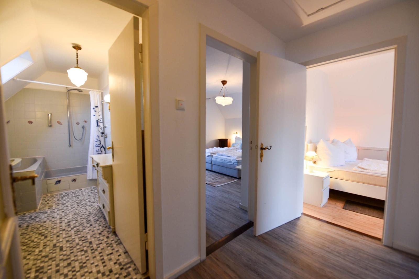 Durchgang zu Schlafzimmer und Bad mit Dusche und Badewanne.