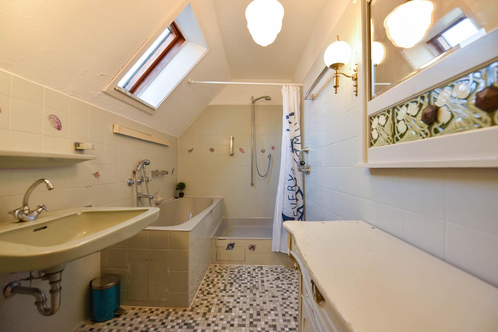 Badezimmer mit Dusche, Badewanne, Waschbecken und Spiegel