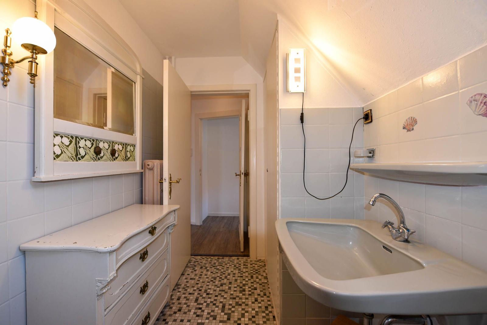 Badezimmer mit Waschbecken, Spiegel und Fliesenboden