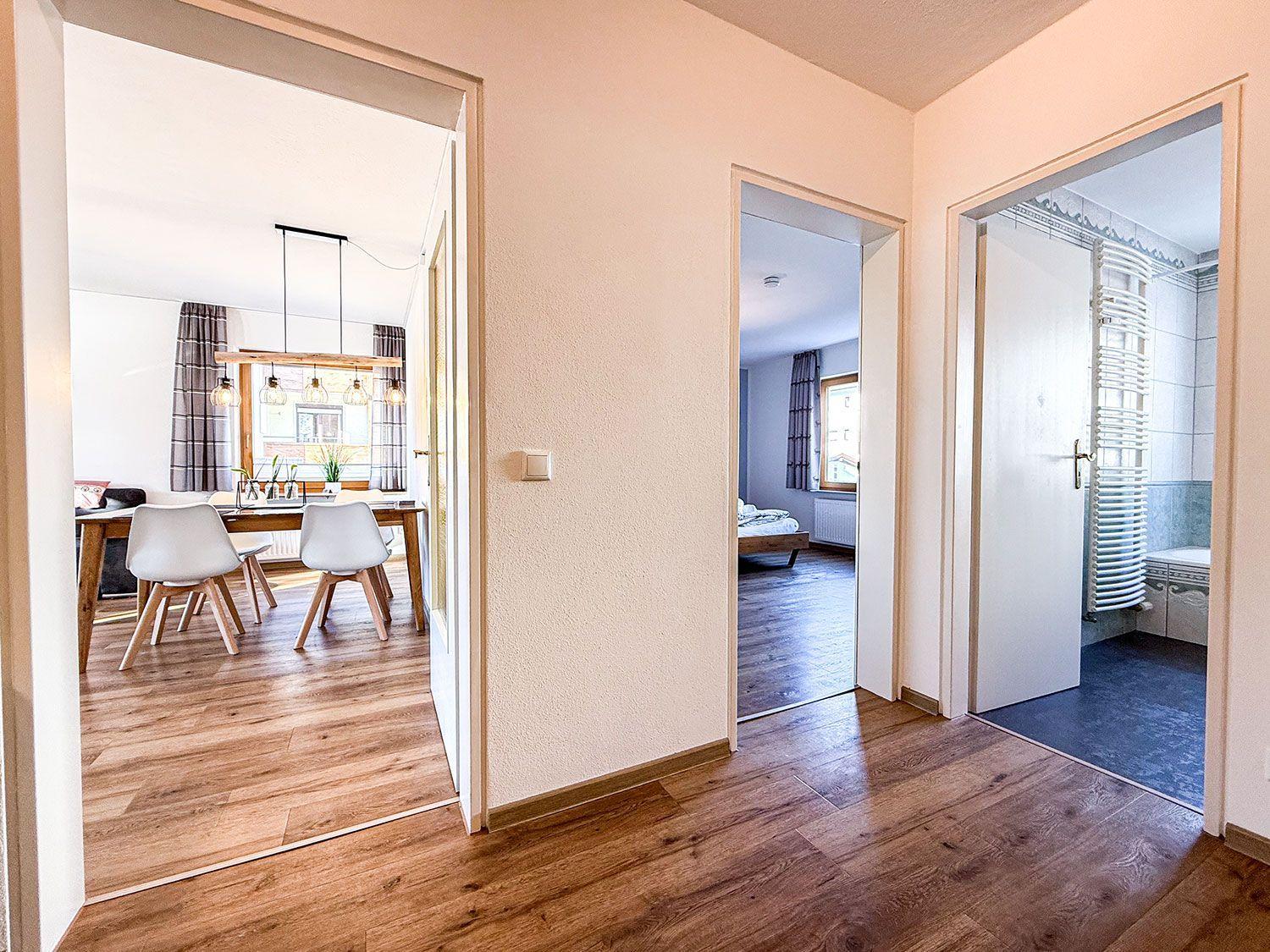 Haus mit Esszimmer, Schlafzimmer und Bad. Holzboden und weiße Wände.