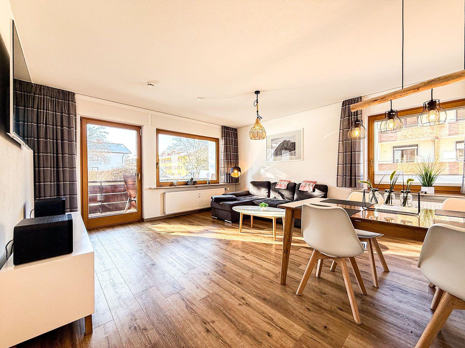 Wohn- und Essbereich mit Holzboden, Sofa, Esstisch und TV.