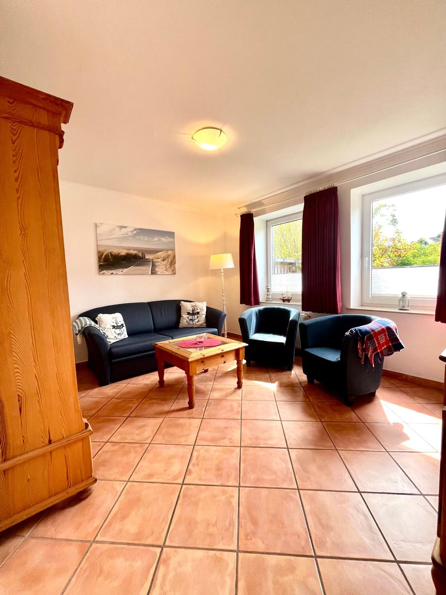 Wohnzimmer mit Sofa, zwei Sesseln, Holztisch und Fenster mit Blick.