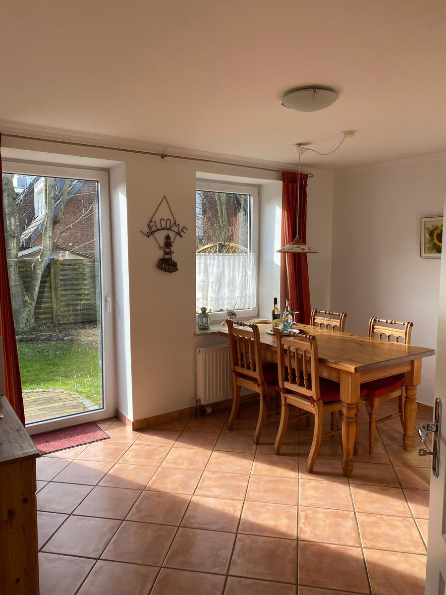 Esszimmer mit Holztisch, Stühlen und Blick auf den Garten.