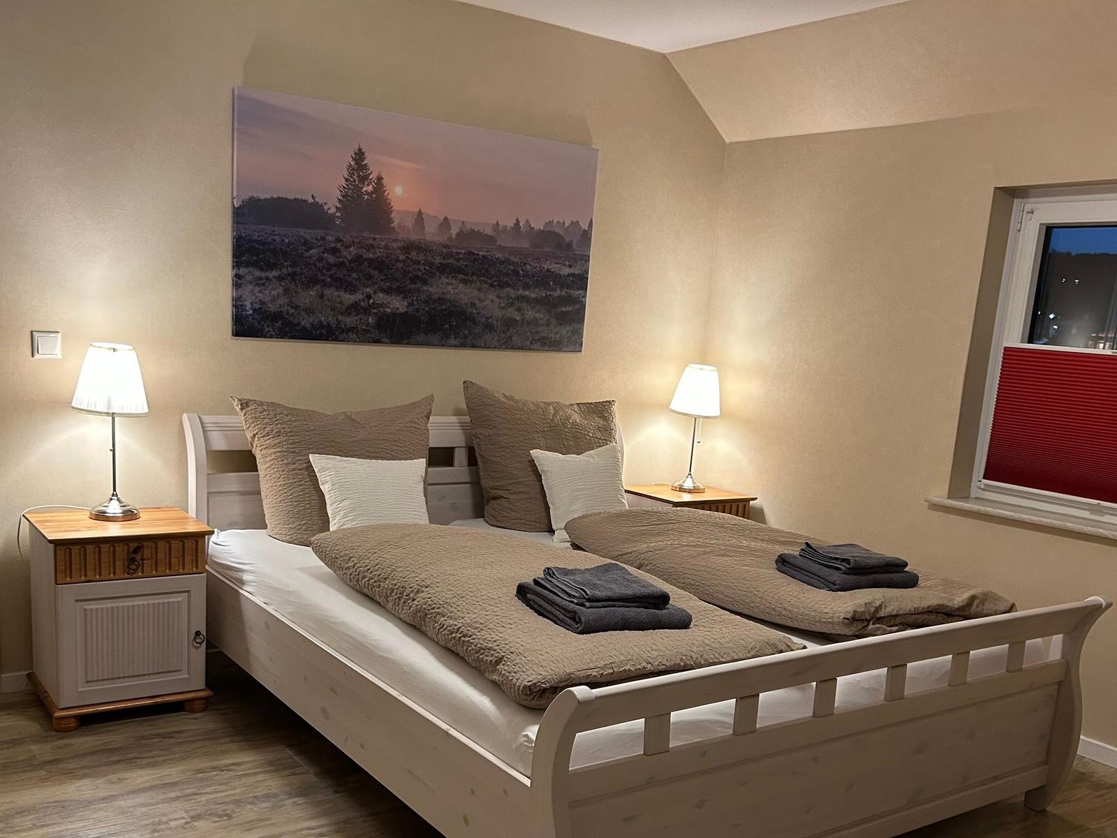 Schlafzimmer mit Doppelbett, zwei Nachttischen und Wandbild.