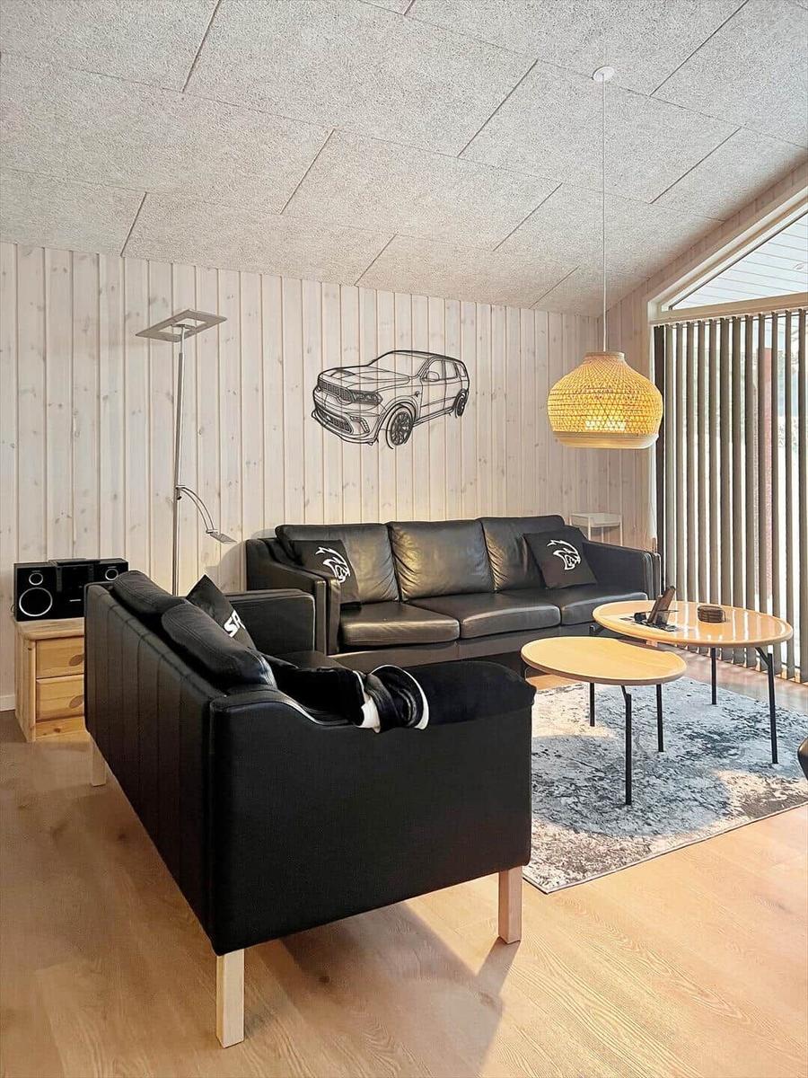 Wohnzimmer mit schwarzen Sofas, Holzmöbeln und Wanddekoration.