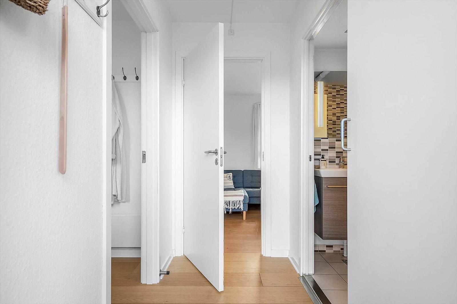 Flur mit Blick in Schlafzimmer und Badezimmer. Holzboden und weiße Wände.