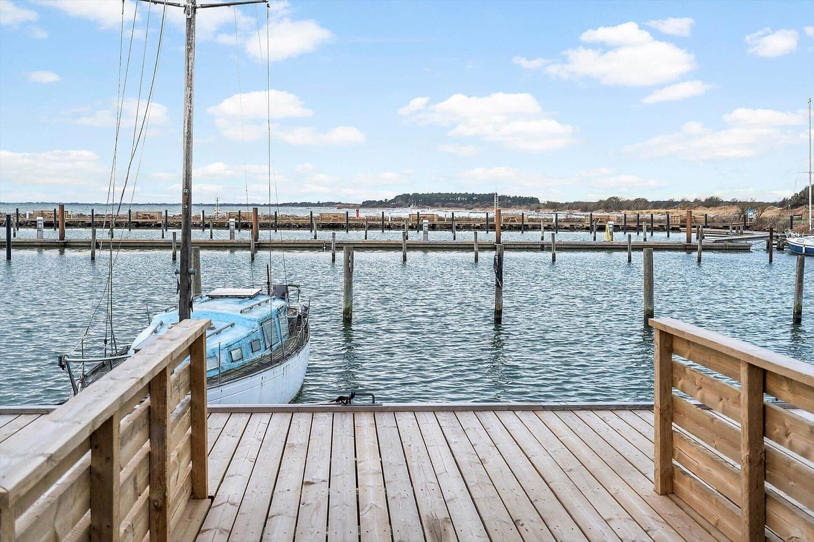Holzterrasse mit Blick auf Hafen und Boot.