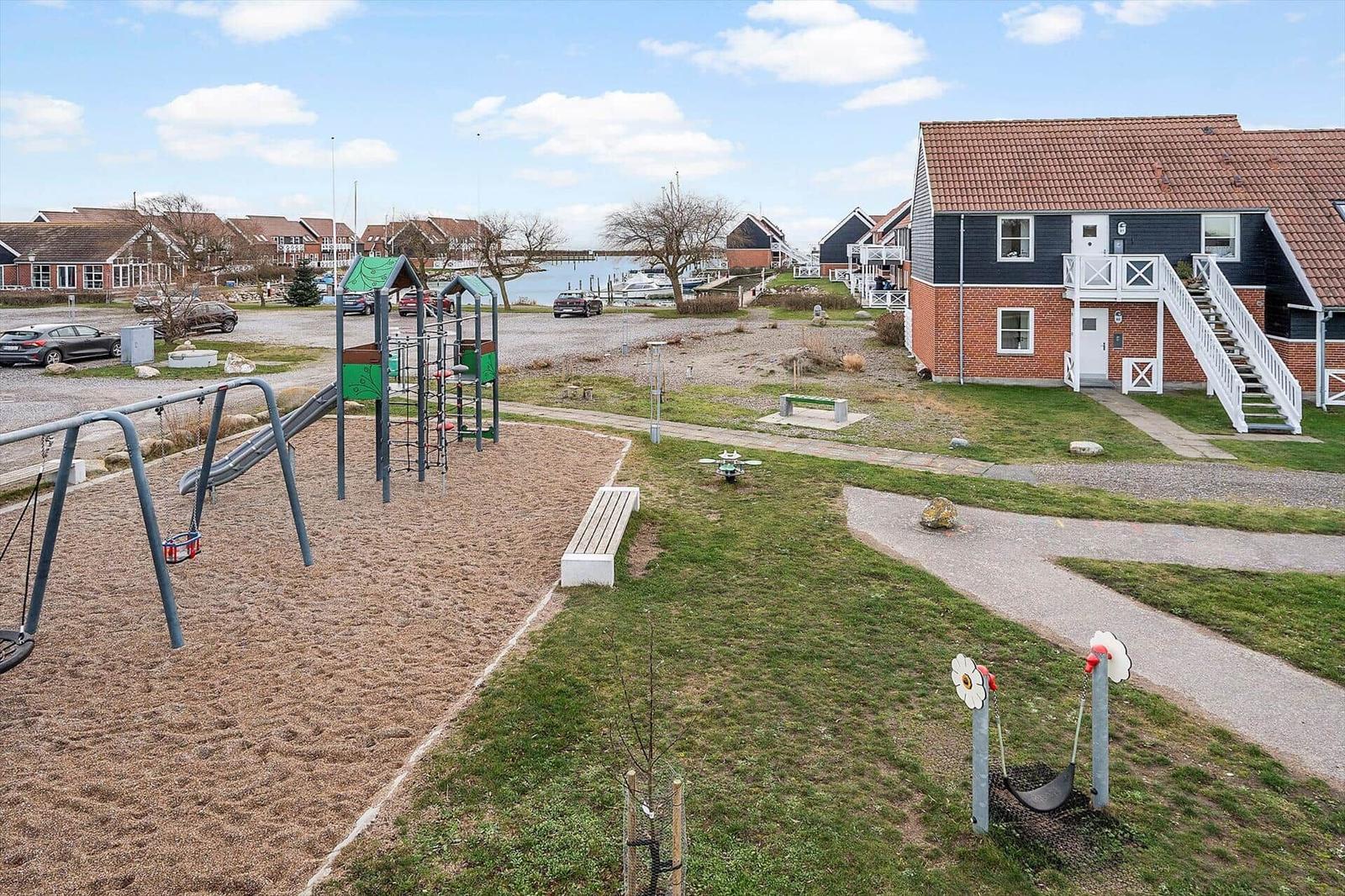 Kinderspielplatz mit Rutsche und Schaukel neben einem Haus mit rotem Dach.