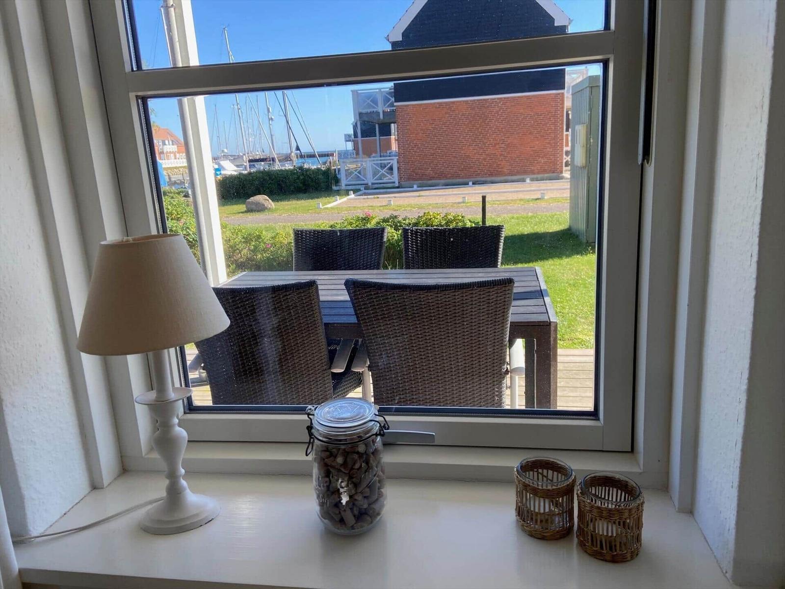 Durch das Fenster ist ein Garten mit Tisch und Stühlen zu sehen.