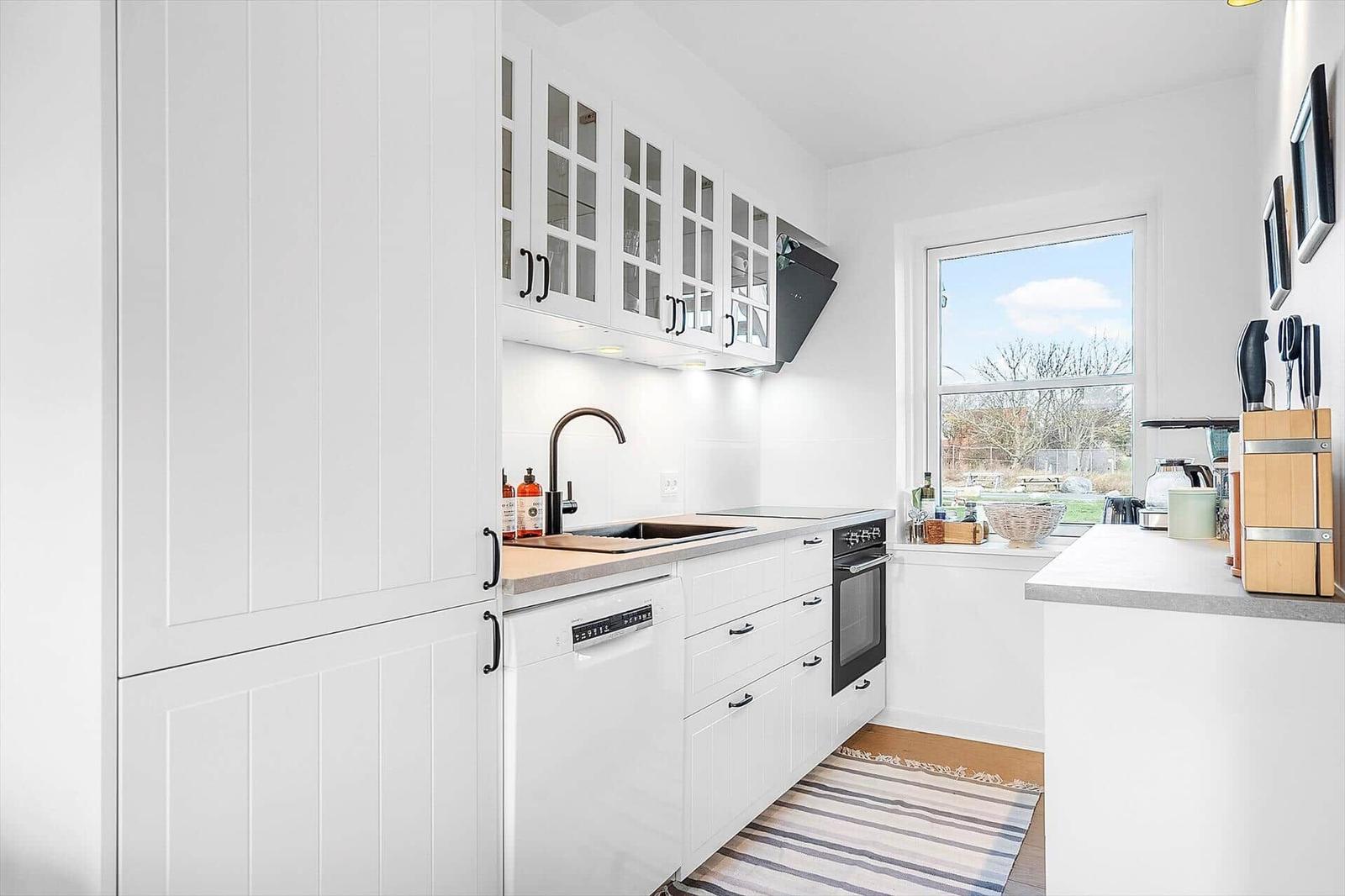 Küche mit weißen Schränken, Fenster und Kücheninsel.