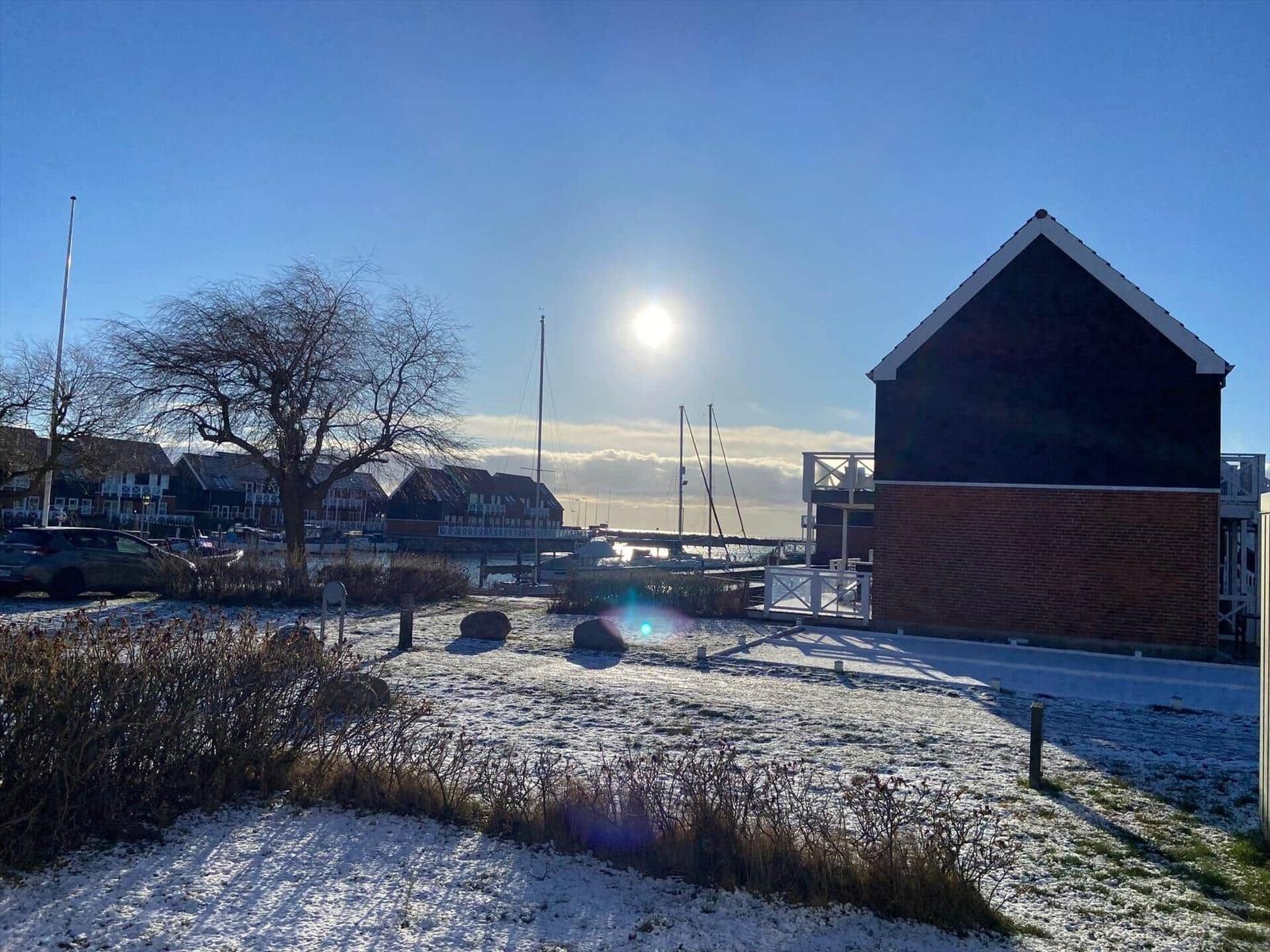 Schneebedeckter Garten mit Blick auf Hafen und Segelyachten.