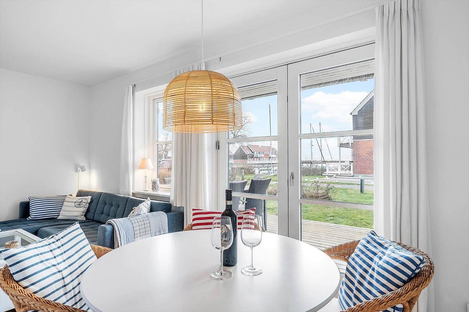 Ein Essbereich mit runden Tisch und Stühlen. Durch Fenster ist Blick auf Außenbereich.