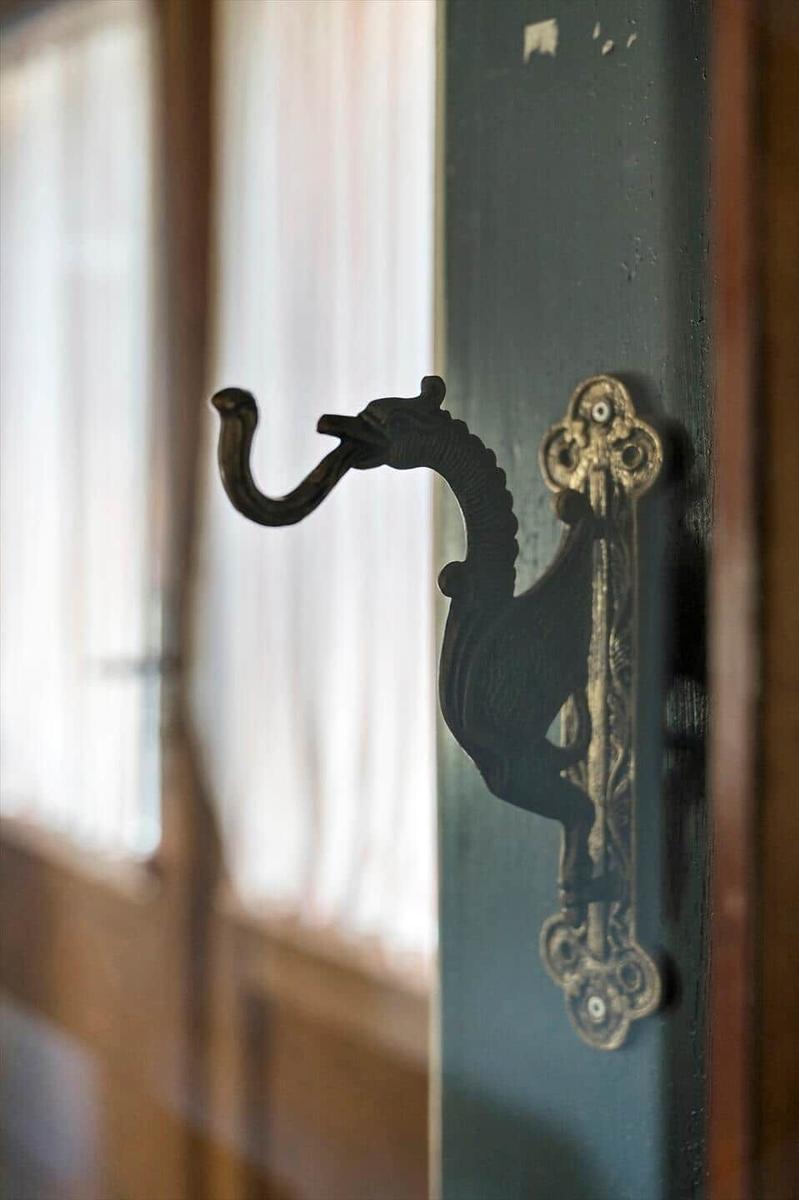 Antik wirkender Haken in Form eines Drachen an einer Tür.