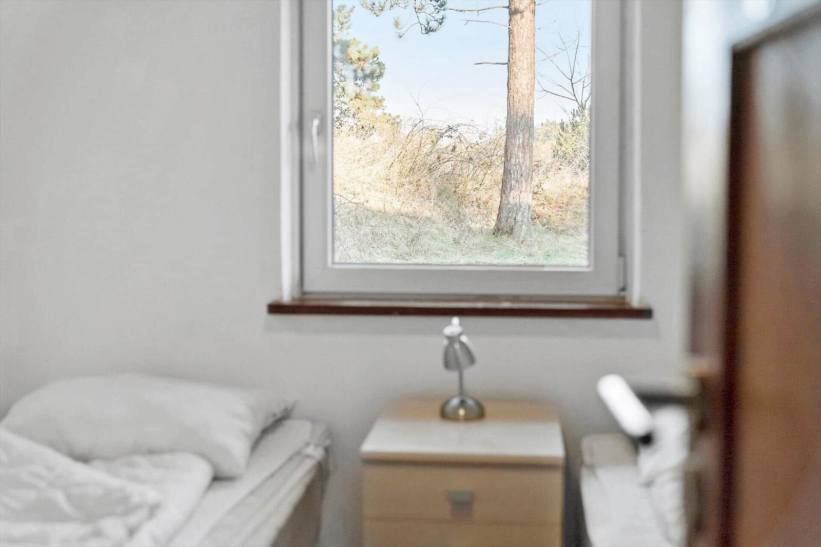 Schlafzimmer mit Fensterblick auf Baum und Gras
