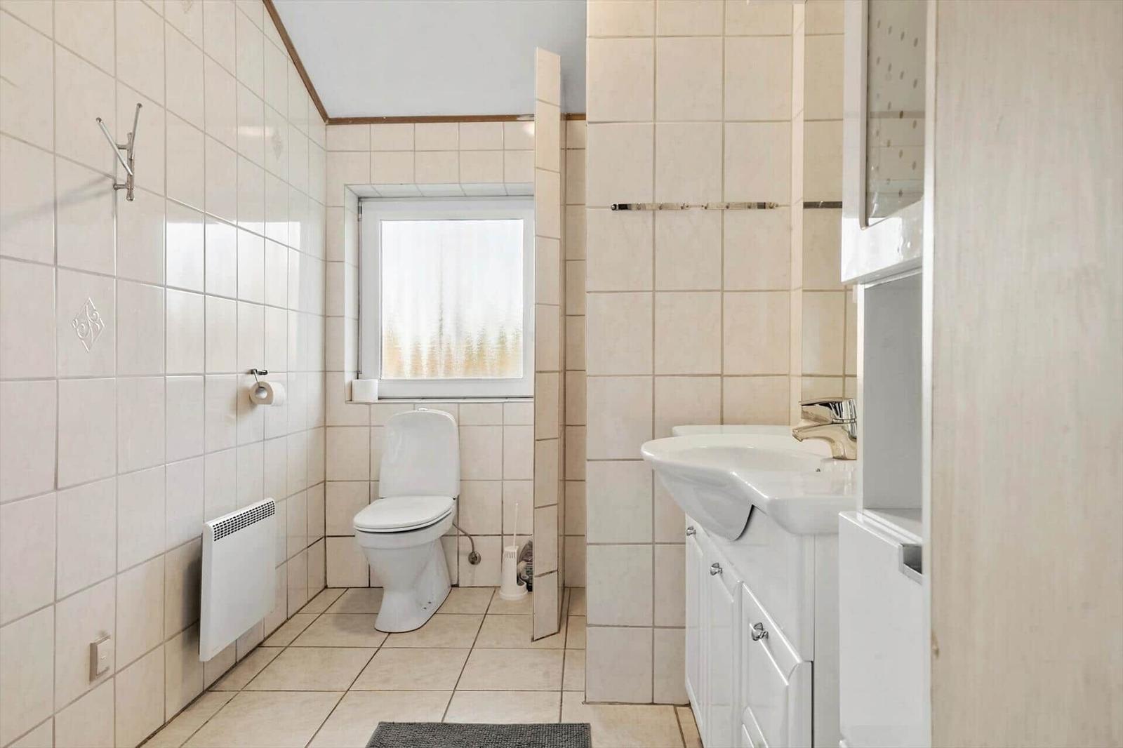 Badezimmer mit Toilette, Waschbecken und Fenster.