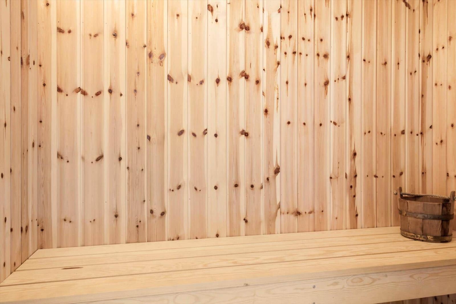 Holzwand mit Sitzbank und Eimer in Sauna