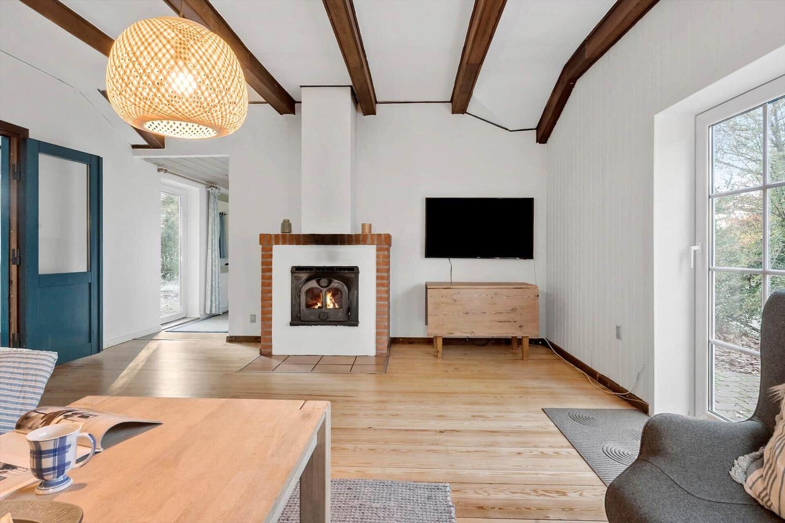 Wohnzimmer mit Kamin, Fernseher und Holzboden.