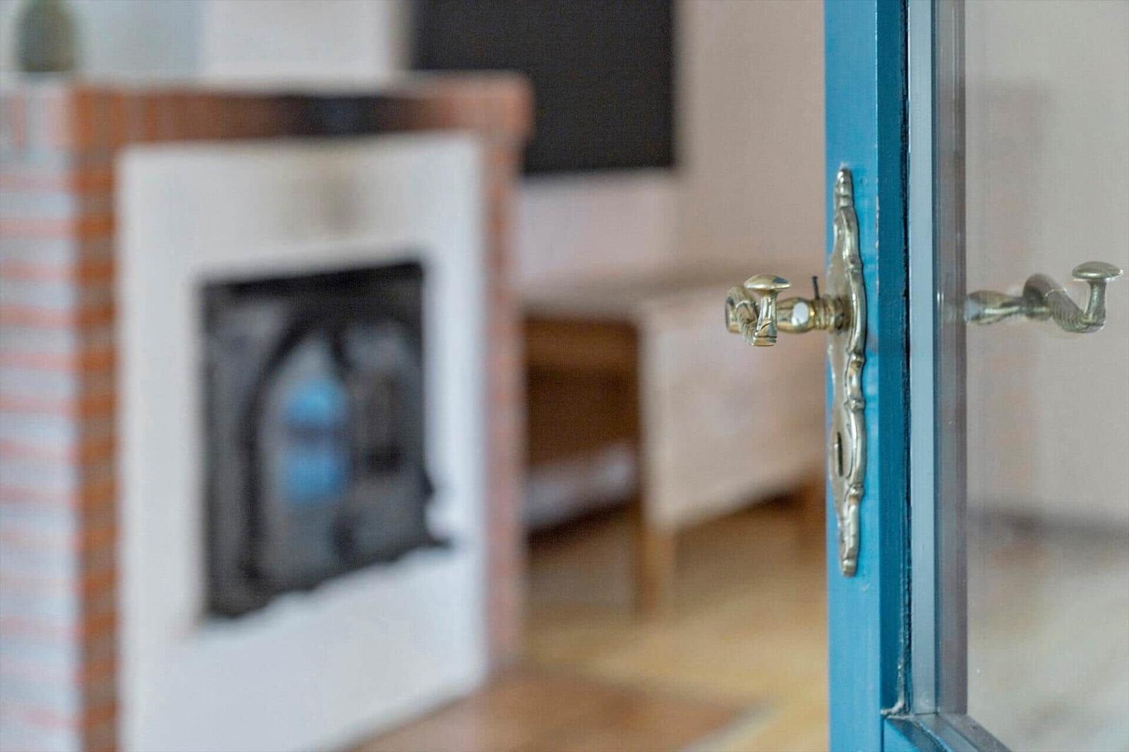 Tür mit Metallgriff führt in einen Raum mit Kamin und Fernseher.