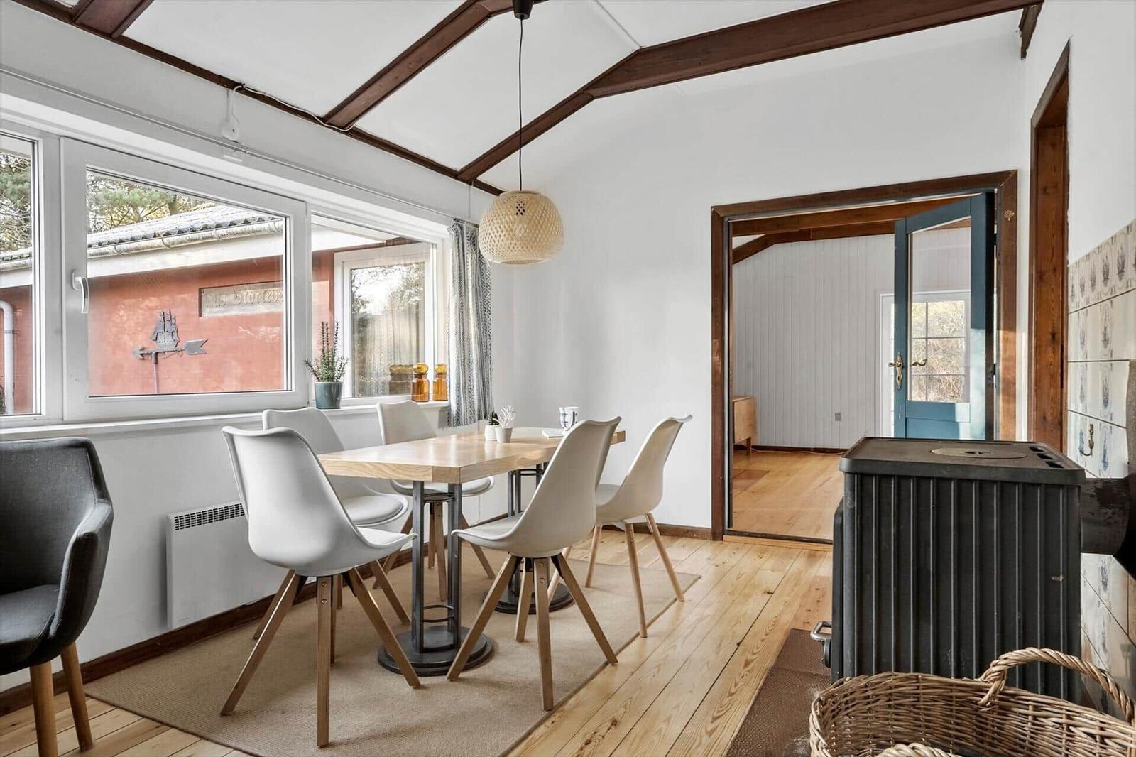 Esszimmer mit Holzboden, Tisch und Stühlen, Fenster und Durchgang.