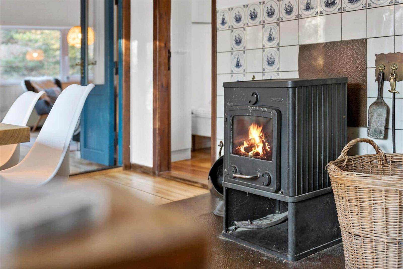 Holzofen mit brennendem Feuer an Wand mit Schiffstapeten.