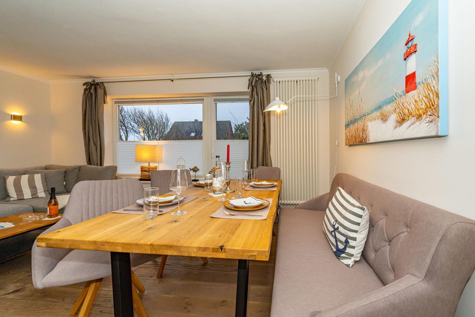 Essbereich mit Holztisch und Sofa, Wandbild mit Leuchtturm