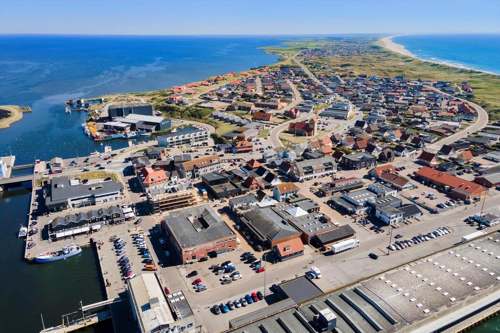 Aerial view of coastal town with harbor, beaches, and residential areas.