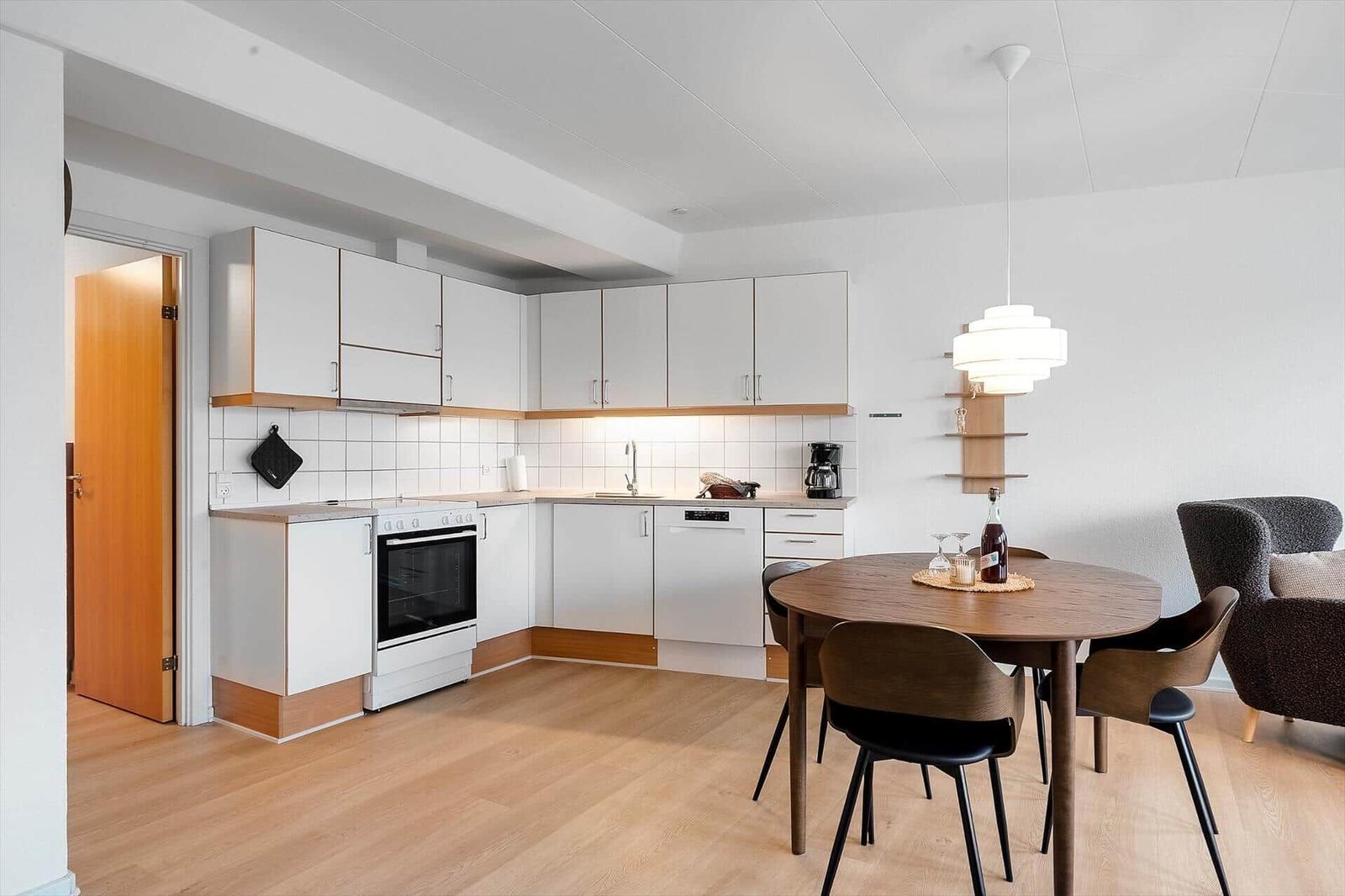 Küche mit Essbereich, Holzboden und weißen Schränken.