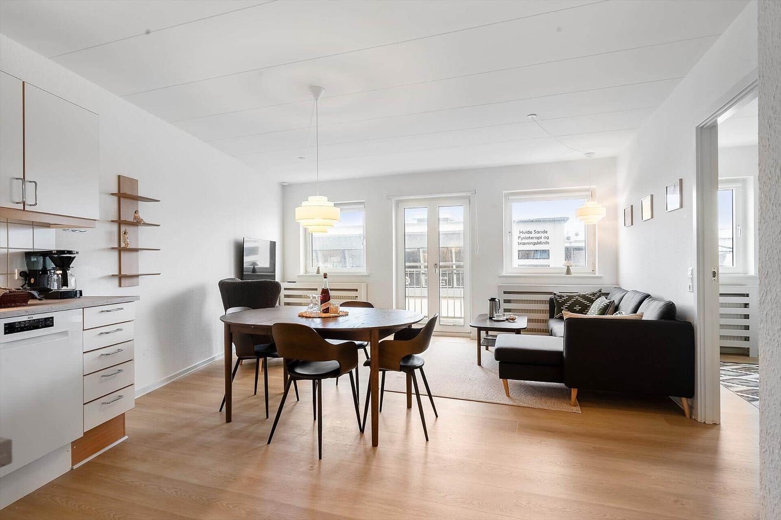 Wohn- und Essbereich mit Esstisch, Sofa und Küchenzeile.