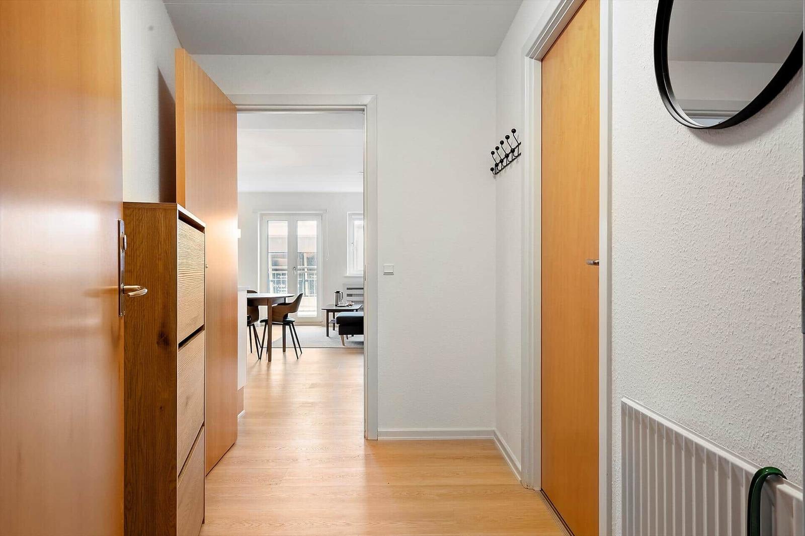 Flur mit Holztüren und -möbeln, Blick in Essbereich mit Tisch und Stühlen.
