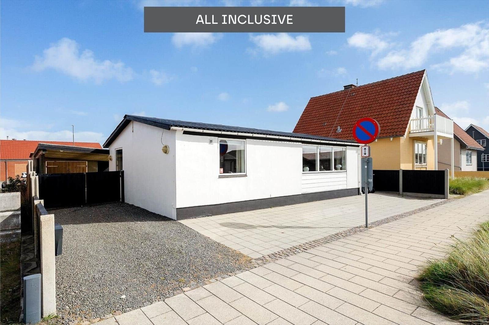 Wohnhaus mit Garage und gepflastertem Weg unter blauem Himmel.