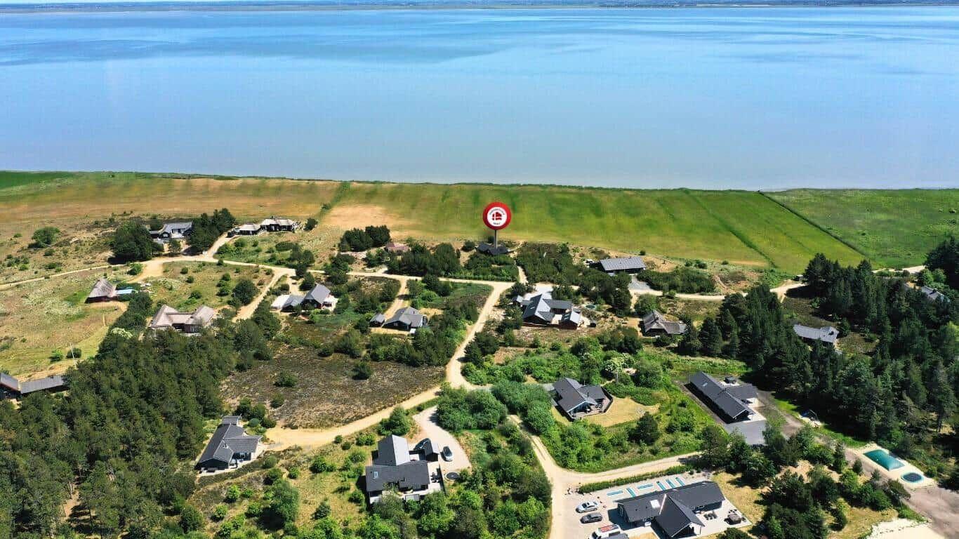 Luftbild von Ferienhäusern am Ufer eines Sees mit Wald und Wegen.