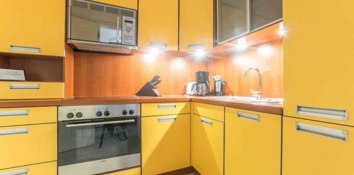 Küche mit gelben Schränken, Edelstahlherd und Mikrowelle