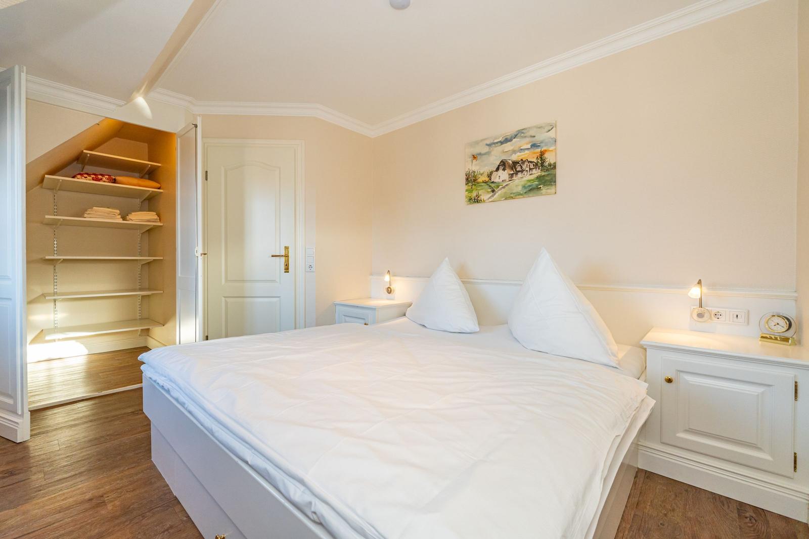 Schlafzimmer mit Bett, Nachttischen und Kleiderschrank. Wandbild und Holzboden.