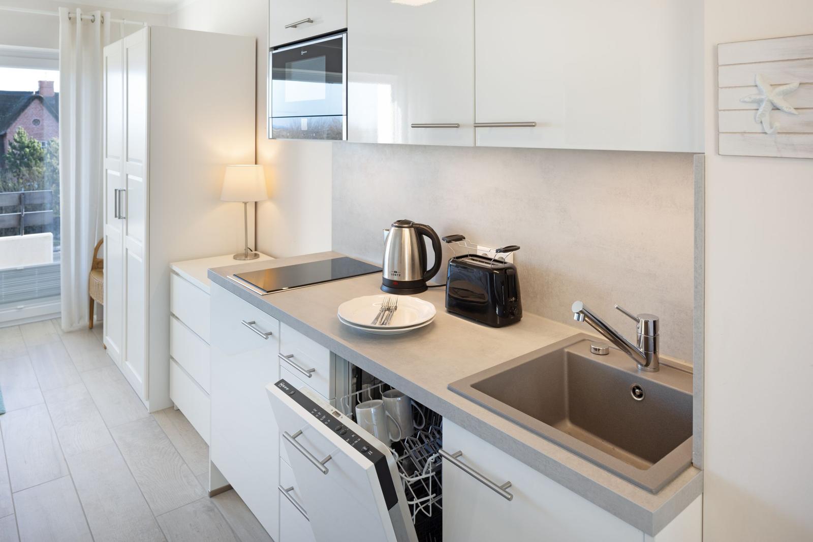 Moderne Küche mit Spüle, Kochfeld und integriertem Kühlschrank.