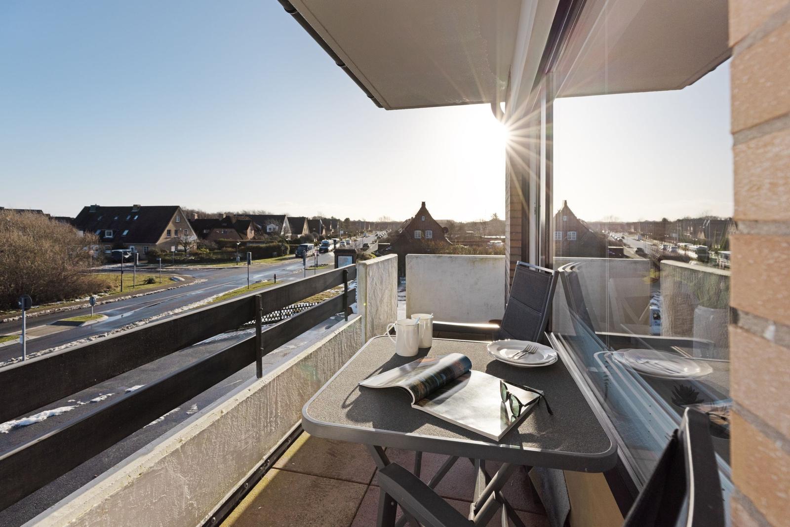 Terrasse mit Tisch, Stühlen und Blick auf Straße und Häuser.