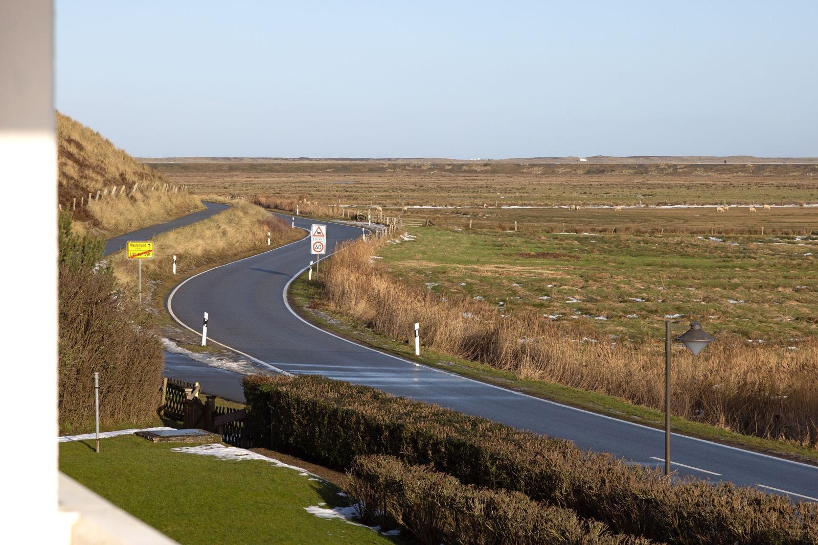 Sicht auf eine Straße mit Feldern und Wegweiser zur Weststrand.